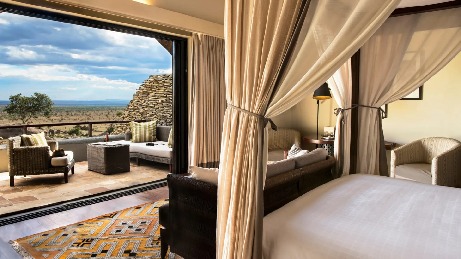 Canopy-bed suite with a stone tower balcony view, part of the luxury lodge tier