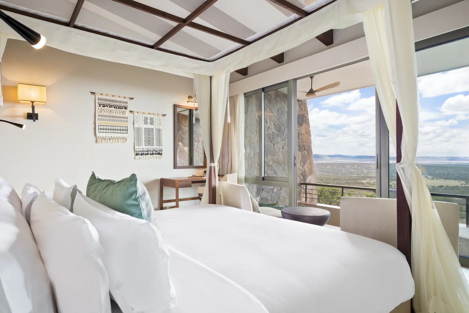 A second room style at Serengeti Lodge (Melia Collection), with a four-poster bed, stone accent wall, and private balcony