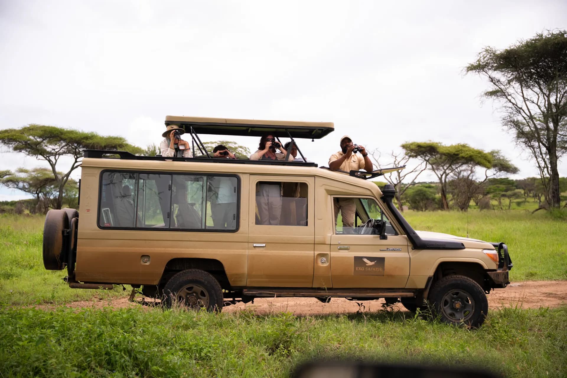 A photographer crouched beside a stream in Tanzania, shooting wildlife with a large telephoto lens
